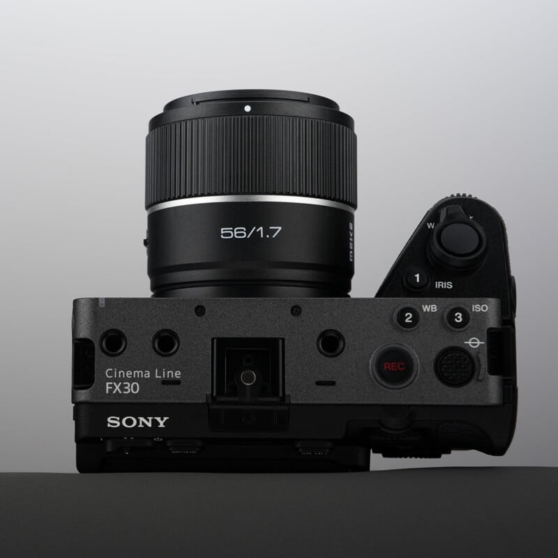 A Sony Cinema Line FX30 camera with a 56mm f/1.7 lens is shown from above, displaying its controls, buttons, and dials against a neutral grey background.