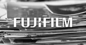 A stack of printed photographs in black and white with the word "FUJIFILM" in bold white letters overlaid in the center.
