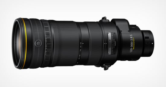 A close-up of a Nikon NIKKOR 120-300mm f/2.8 S telephoto zoom lens, featuring a black body with a textured grip, gold ring, and engraved specifications.