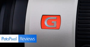 Close-up of a camera lens with a red "G" logo. The "PetaPixel Reviews" logo is in the bottom left corner.