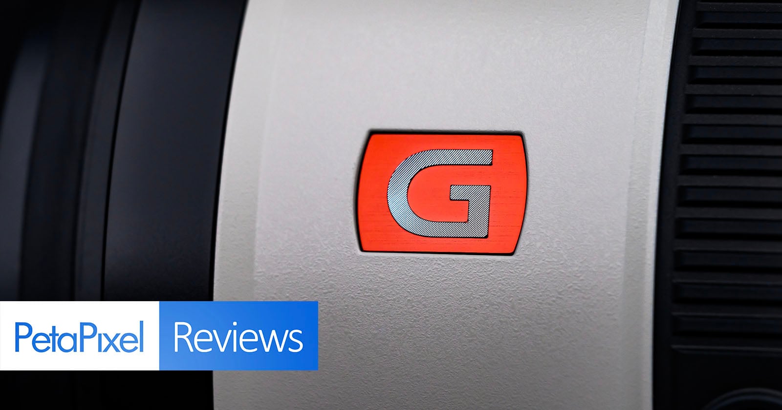 Close-up of a camera lens with a red "G" logo. The "PetaPixel Reviews" logo is in the bottom left corner.