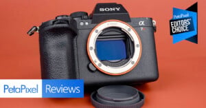 A Sony α7R camera body without a lens is displayed on an orange background with its body cap off. "PetaPixel Reviews" and "Editors' Choice" graphics are overlaid on the image.