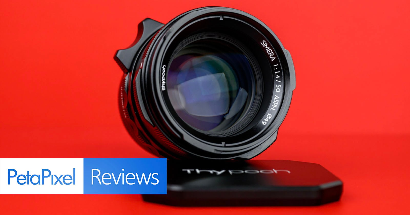 A camera lens with "SINEAR 1:1.4/50 ASPH Ø49" inscribed on it is shown against a bright red background. The lens cap marked "Thypoch" lies in front. "PetaPixel Reviews" is displayed in the bottom left corner.