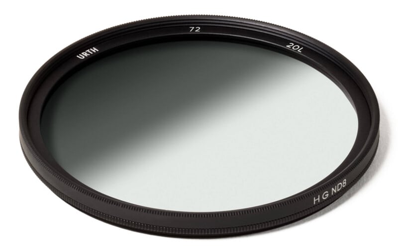 A round camera lens filter with a black metal rim, labeled “URTH,” “72,” “20L,” and “H G ND8.” The glass has a gradient, transitioning from dark to clear. The filter rests on a white background.