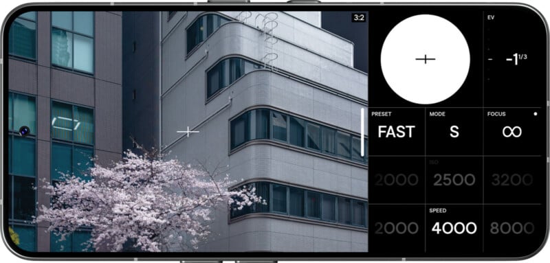 A smartphone screen displays a camera app interface; on the left, a cherry blossom tree stands in front of a modern gray building, while camera settings such as shutter speed and ISO appear on the right.