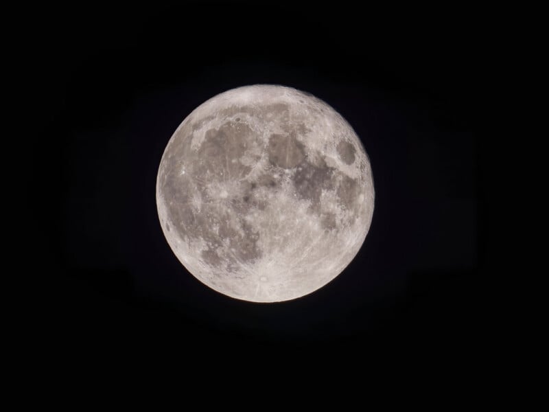 A close-up view of a full moon against a black night sky, showing detailed craters and surface features.