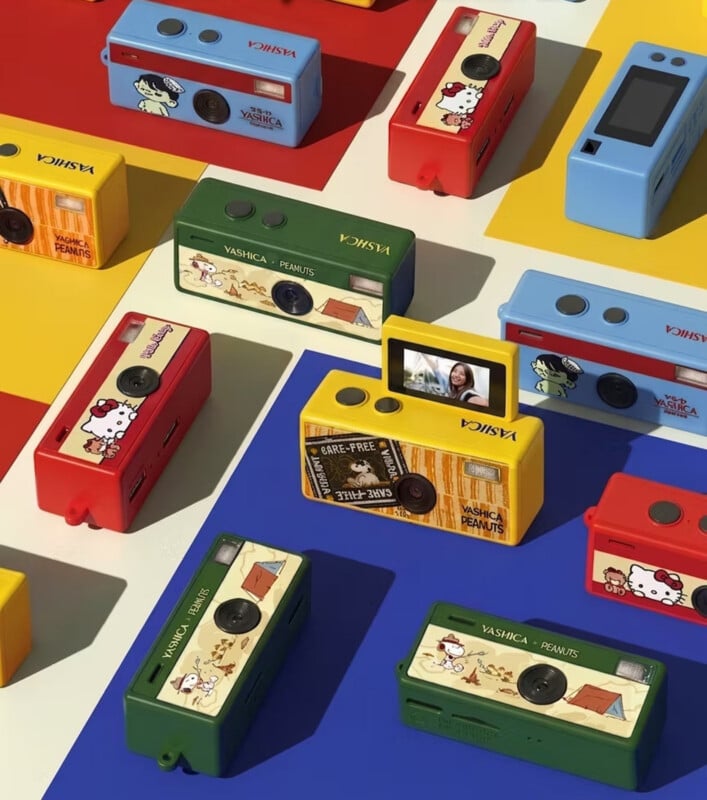 Colorful Yashica Peanuts cameras in red, yellow, green, and blue are arranged on a vibrant, patterned background. Each camera features Peanuts or Hello Kitty designs, with one yellow camera showing a digital screen.