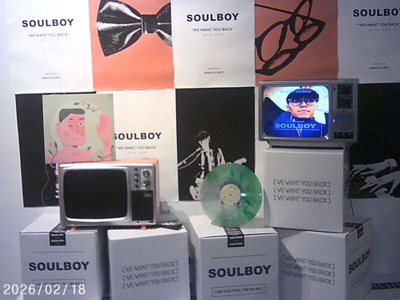 A display features vintage TVs, album covers, a green vinyl record, and stacks of boxes labeled "SOULBOY (WE WANT YOU BACK)." One TV displays a person’s face and "SOULBOY." Posters and art decorate the background. Date: 2026/02/18.