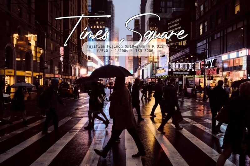 People with umbrellas cross a wet street in Times Square at dusk, surrounded by glowing billboards and tall buildings. The scene feels vibrant and busy despite the rain. Text overlay provides camera settings and the location name.