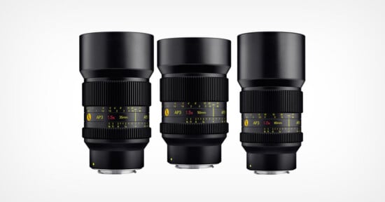 Three black camera lenses with yellow and white markings are standing upright side by side against a plain white background. Each lens displays different focal lengths and aperture information on their barrels.