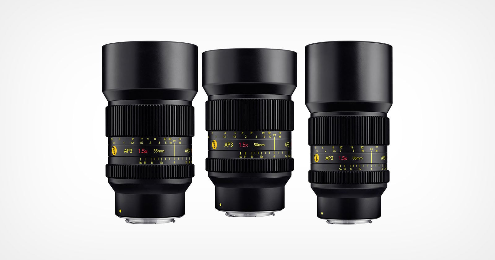 Three black camera lenses with yellow and white markings are standing upright side by side against a plain white background. Each lens displays different focal lengths and aperture information on their barrels.