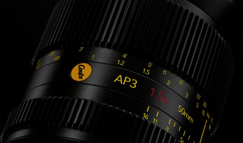 Close-up of a camera lens showing the brand "Cooke" in yellow, with "AP3", "1.5x", and "50mm" marked in yellow and red text. Black focus and aperture rings with engraved numbers are also visible.