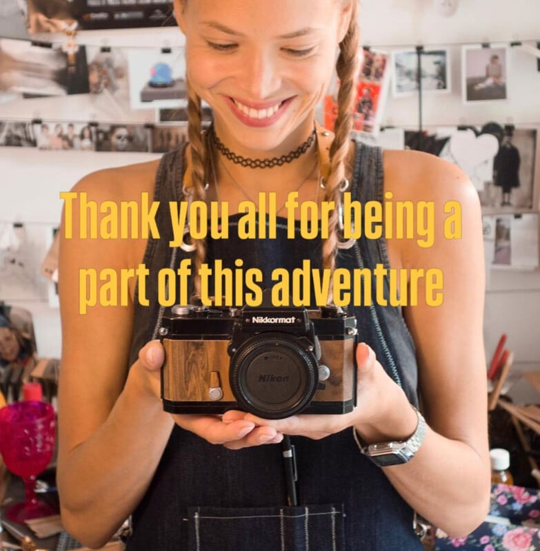 A smiling person with braided hair holds a vintage Nikomat camera. Yellow text over the image reads, "Thank you all for being a part of this adventure." The background shows photos and creative tools.