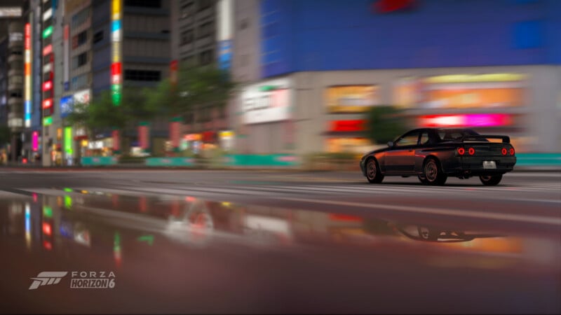 A black sports car speeds through a brightly lit city street at night, with colorful neon signs and buildings blurred in the background, reflected on the wet road. The Forza Horizon 6 logo appears in the corner.