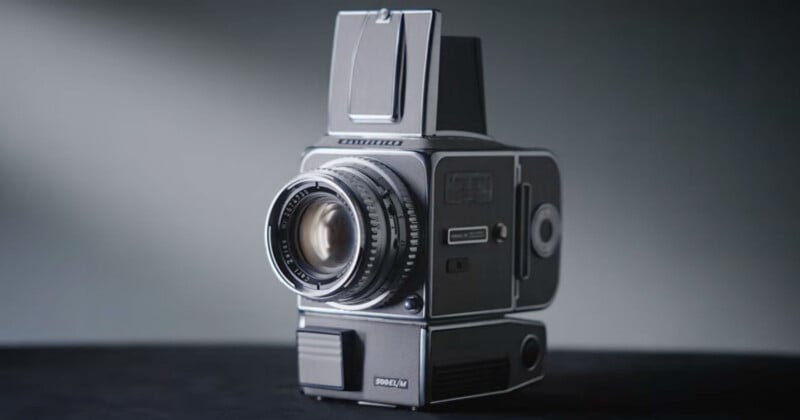 A vintage medium format camera with a large lens and waist-level viewfinder sits on a dark surface against a softly lit background.