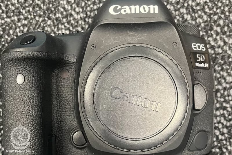 A close-up of a Canon EOS 5D Mark IV camera body with a lens cap on, placed on a textured, black-and-white carpet. The NSW Police Force logo is visible in the lower left corner.