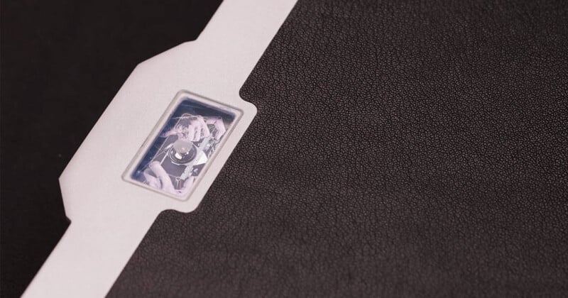 A close-up of a textured black and white surface with a small transparent window revealing a mechanical component or sensor inside.