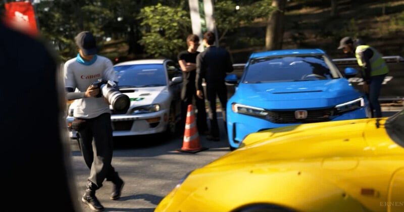 A photographer with a large camera walks near parked sports cars, including a blue Honda and a yellow car. Several people stand and talk near the cars on a sunlit street with trees in the background.
