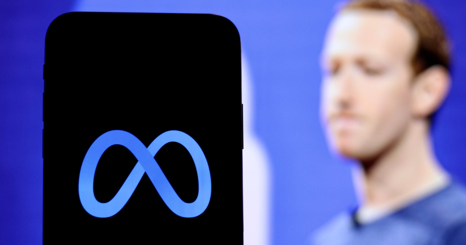A smartphone displays the Meta logo in the foreground, with a blurred person standing against a blue background in the distance.