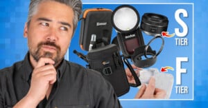 A man with a thoughtful expression stands next to a collage of camera gear labeled “S tier” and “F tier” on a blue background, with various photography accessories and lenses shown.