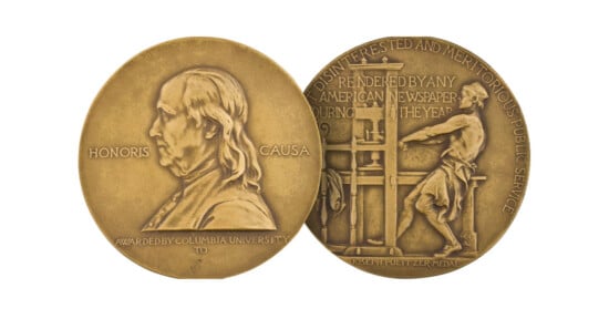 Two sides of a gold Pulitzer Prize medal: one shows Benjamin Franklin’s portrait with "Honoris Causa," the other depicts a man at a printing press with engraved text about American journalism.