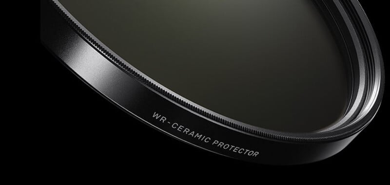 Close-up of a black camera lens filter labeled "WR-CERAMIC PROTECTOR" against a black background.
