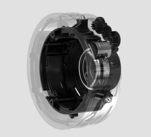 A semi-transparent view of a circular mechanical device, showing internal gears and components, highlighting the intricate machinery and engineering within a cylindrical casing.