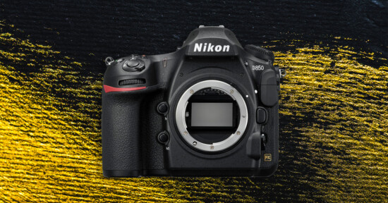 A Nikon D850 DSLR camera body without a lens is displayed against a textured black and yellow background. The camera’s sensor is visible in the center where the lens would attach.