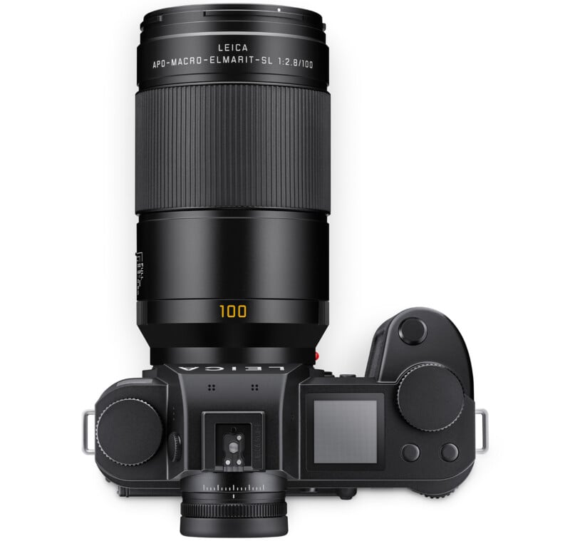 Top view of a black Leica camera with an attached 100mm APO-Macro-Elmarit-SL lens; various control dials, buttons, and a screen are visible on the camera body.