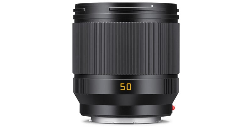 A black camera lens with a ribbed focus ring and a yellow "50" marking on the barrel, indicating a 50mm focal length, is shown standing upright against a white background.