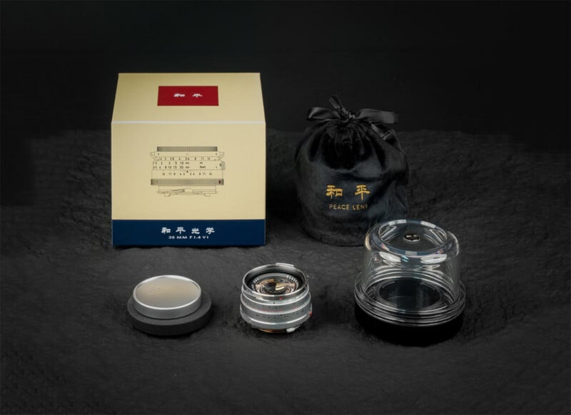 A 35mm camera lens with a lens cap, clear protective case, black drawstring pouch, and a beige and gold product box featuring lens graphics and Chinese characters, all displayed on a dark textured surface.