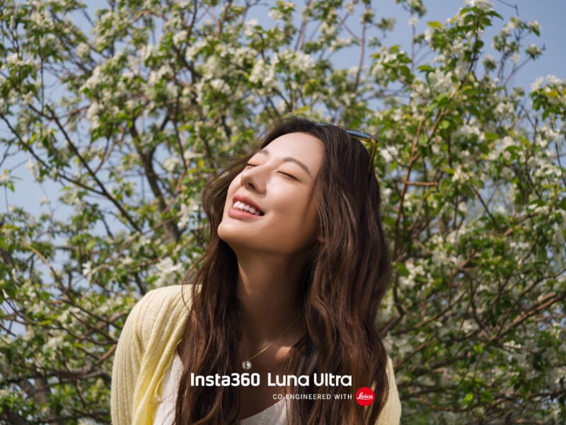 A woman smiles with her eyes closed, standing outdoors in front of a blooming tree under a blue sky. Text at the bottom reads "Insta360 Luna Ultra co-engineered with Leica.