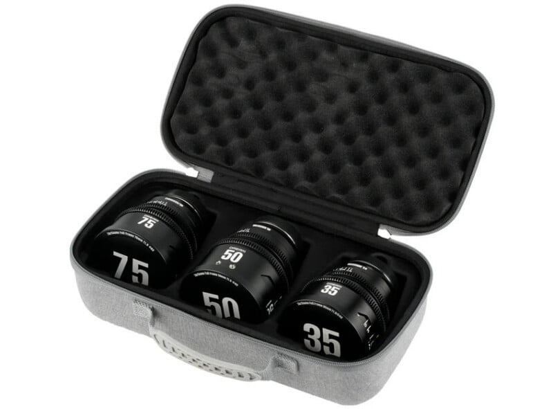 A gray protective case with foam padding holds three camera lenses labeled 75, 50, and 35, arranged neatly inside. The case lid is open, revealing the lenses and textured foam interior.