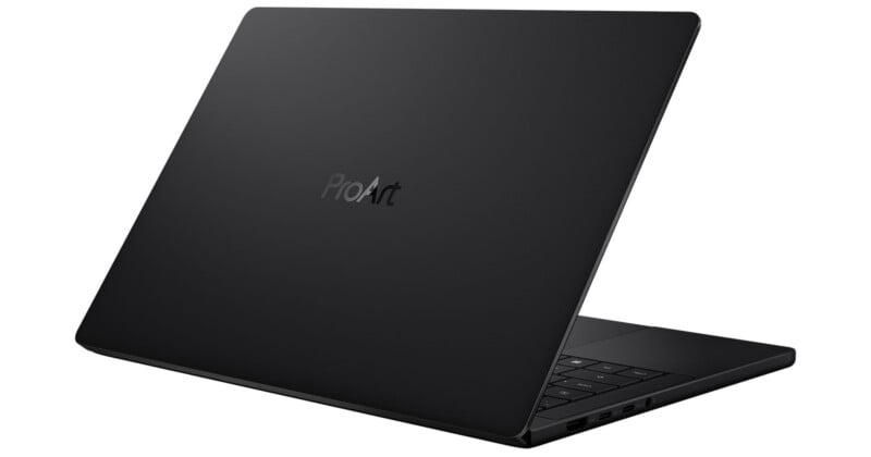A sleek black laptop partially open, viewed from behind at an angle, with "ProArt" branding on the back of the lid. The edge of the keyboard and several side ports are visible.