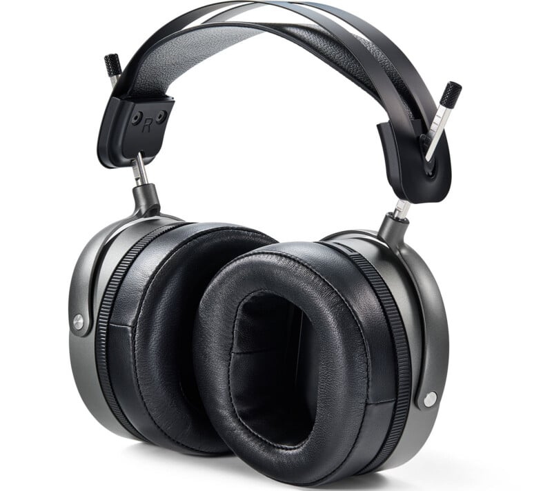 A pair of over-ear headphones with large, cushioned black ear pads and a wide, padded headband featuring metal supports and adjustment knobs on each side.