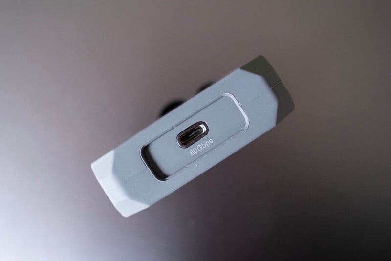 Close-up of a gray electronic device featuring a single USB-C port labeled "80 Gbps" on its side, set against a plain, dark background.