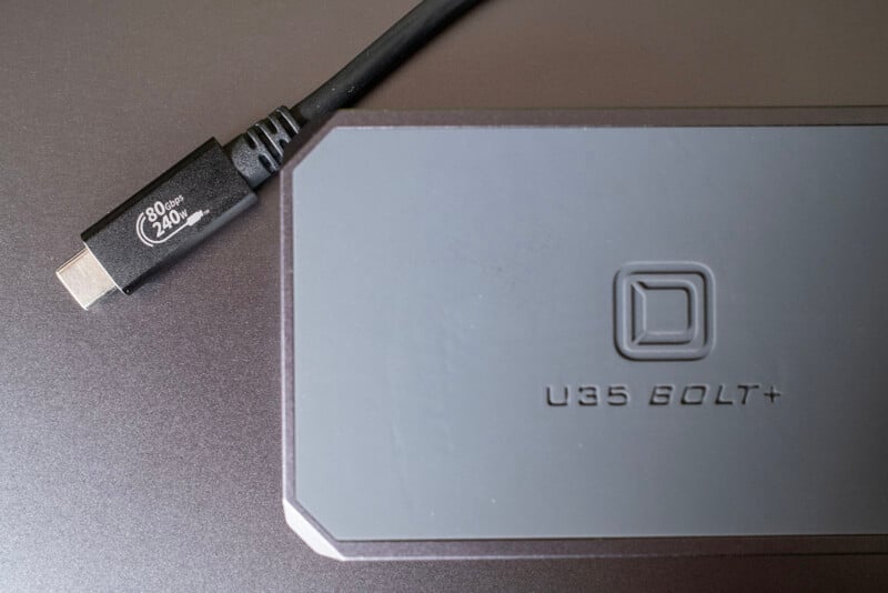 A close-up of a U35 Bolt+ external storage device next to a black USB-C cable labeled "PD 20V 240W." The devices are placed on a smooth, metallic surface.