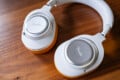 A pair of white and silver Fender over-ear headphones with orange accents rests on a wooden surface.