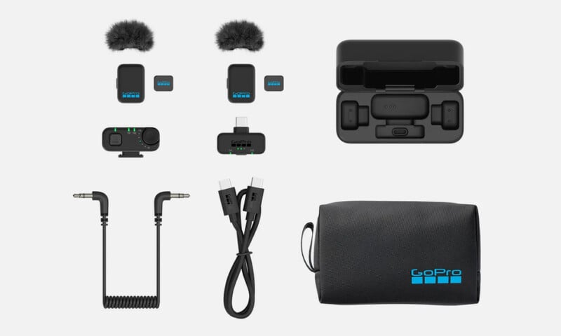 GoPro wireless microphone kit with two microphones, furry windshields, two receivers, charging case, two cables, coiled audio cable, and a black GoPro carrying pouch displayed on a white background.