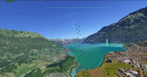 A simulated flight view displays a virtual landscape with mountains, a large blue lake, and a town. Flight instrument overlays are visible on the screen, with clear skies above and a lush green valley below.
