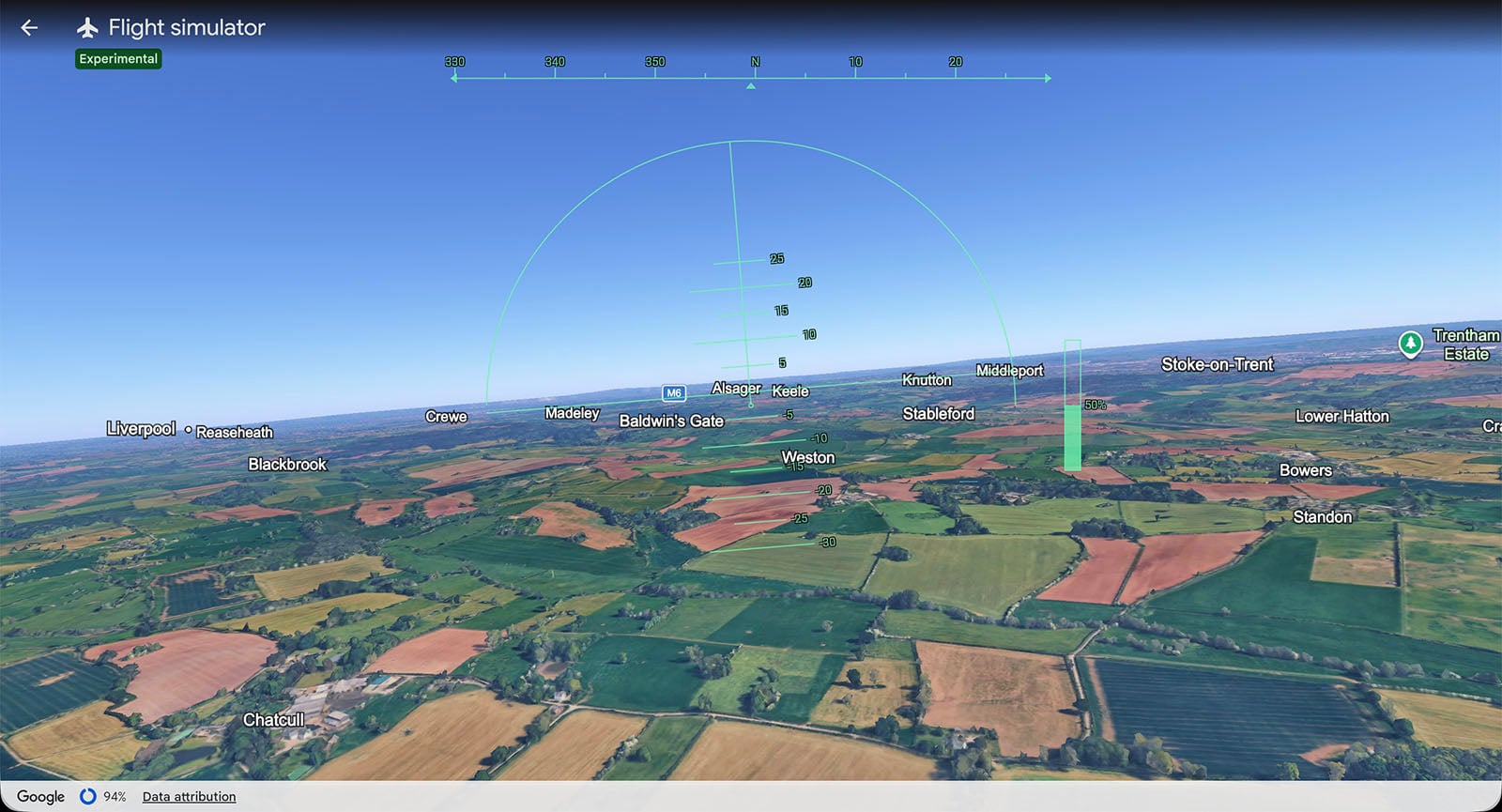 A screenshot of a flight simulator view over a patchwork of green and brown fields, with village names labeled. Navigation graphics and a horizon line are displayed on the screen.