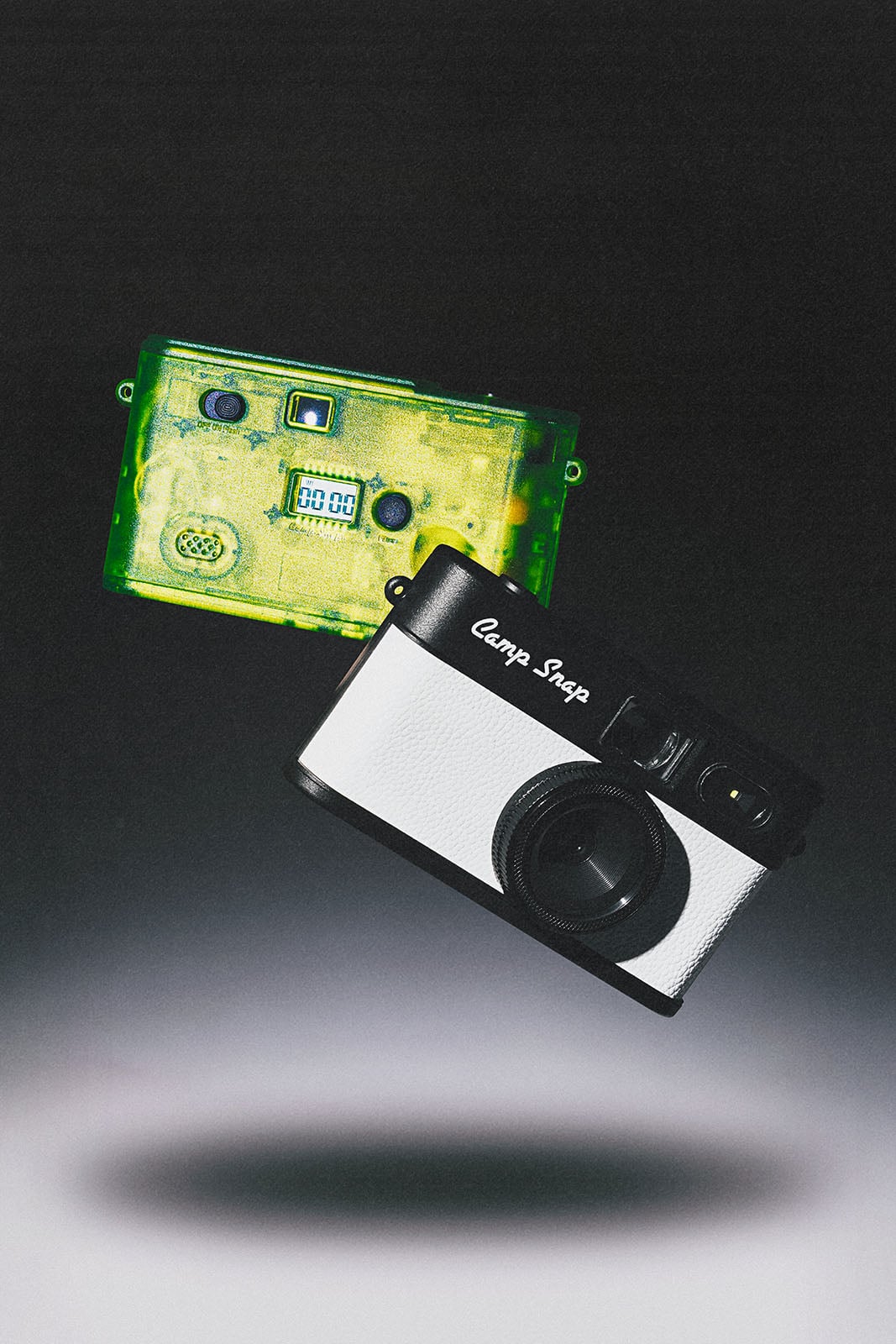 A green transparent cassette tape and a black-and-white camera float against a dark gradient background, casting a soft shadow below.