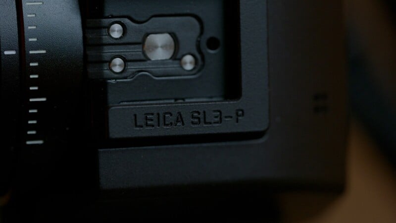 Close-up of a black camera body showing the engraved text "LEICA SL3-P" near a metal mounting bracket.