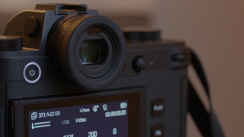 Close-up of a digital camera showing the viewfinder, power button, and part of the screen displaying camera settings such as storage, video mode, and battery level.