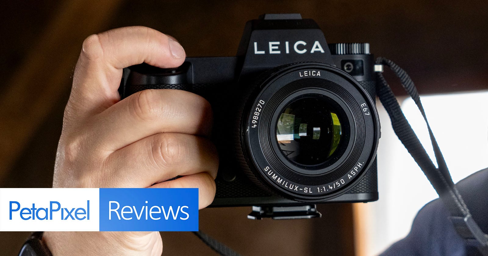 A person holds a Leica camera close to their face, with the lens facing the viewer. The image has "PetaPixel Reviews" text in the lower left corner.