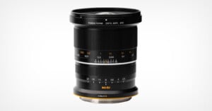 A black NiSi camera lens with orange accents, featuring distance and aperture markings, stands upright against a plain white background.