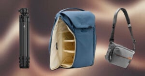 A black tripod, an open blue photography backpack with beige interior, and a small gray crossbody camera bag are arranged side by side on a blurred brown gradient background.