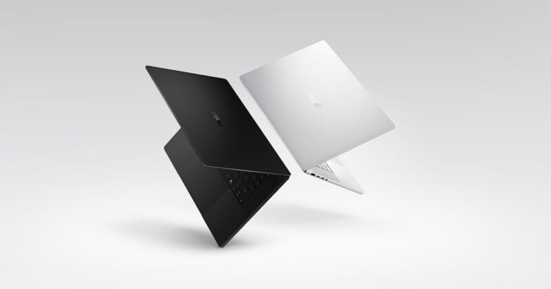 Two slim laptops, one black and one silver, are shown floating in mid-air against a light gray background, both partially open and facing each other with the brand name "realme" visible on their lids.