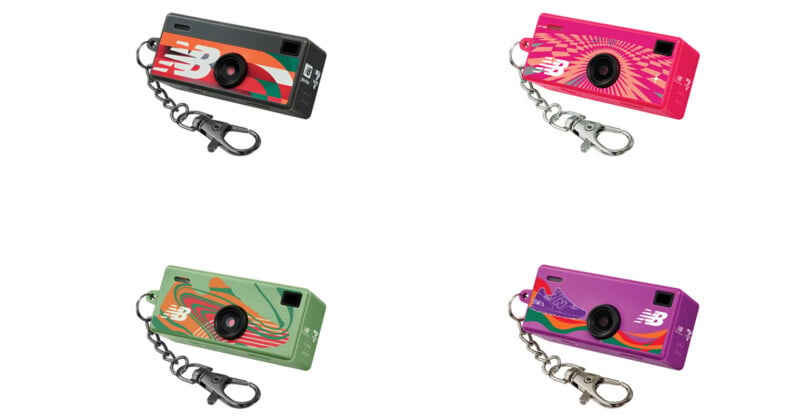 Four colorful, rectangular keychain cameras with different New Balance designs: one black and red, one pink with a swirl pattern, one green with wavy lines, and one purple with a mountain graphic. Each has a key ring and clip.