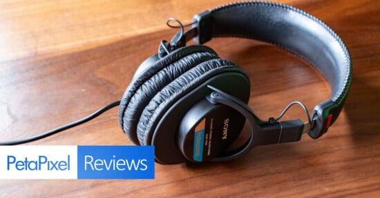 A pair of Sony headphones rests on a wooden surface. The image features "PetaPixel Reviews" text in the bottom left corner, partially overlapping the headphones.